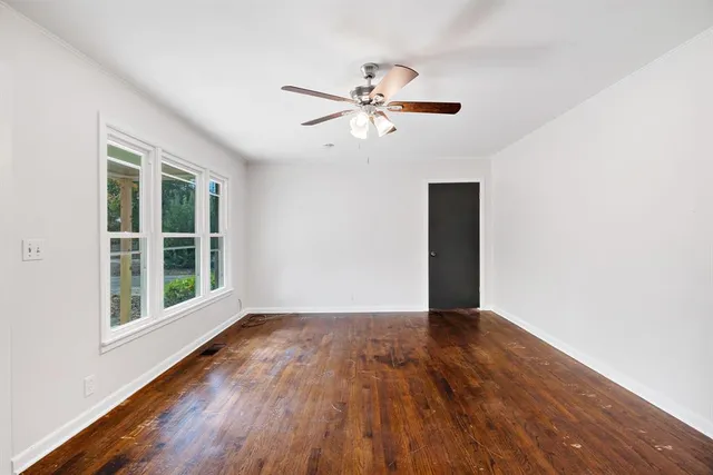 a view of an empty room with wooden floor and a window
