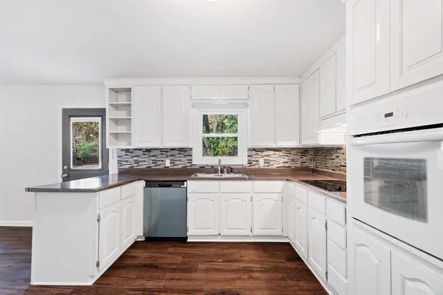 a kitchen with stainless steel appliances white cabinets and wooden floor
