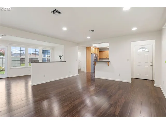 a view of a kitchen with a fridge and wooden floor