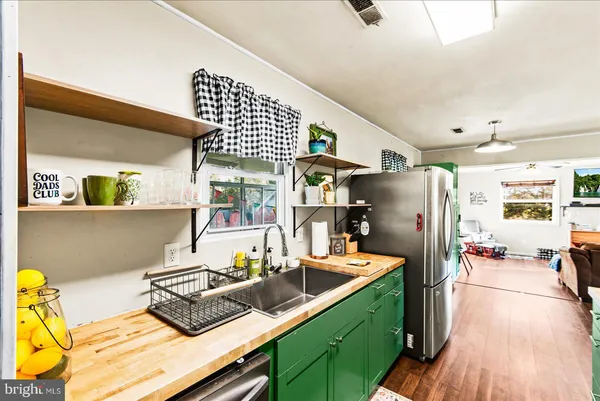 a kitchen with stainless steel appliances kitchen island granite countertop a refrigerator a stove and a wooden floors