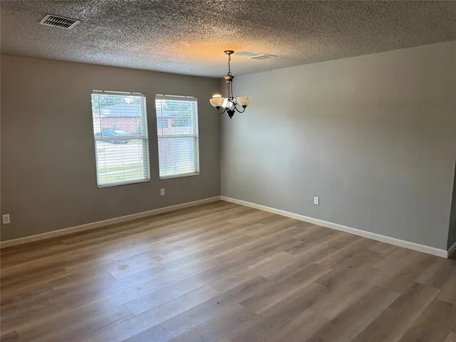an empty room with wooden floor windows and ceiling fan