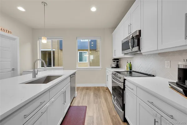 a kitchen with granite countertop a sink a stove top oven and cabinetry