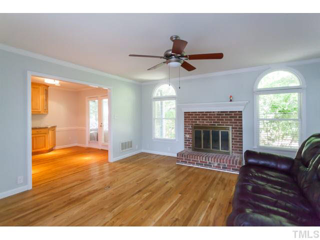 7312 Wilderness Road Raleigh, NC 27613 - Photo 5 of 23 a view of empty room with a fireplace and wooden floor