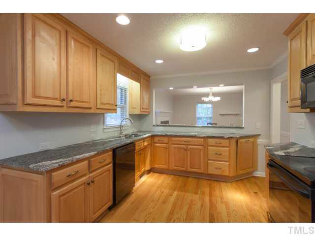 7312 Wilderness Road Raleigh, NC 27613 - Photo 7 of 23 a kitchen with stainless steel appliances granite countertop a stove a sink and a granite counter tops with wooden floors