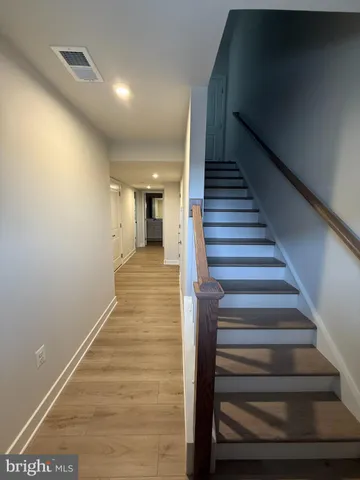 a view of staircase with wooden floor and lots of frames on wall