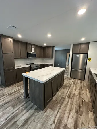 a kitchen with stainless steel appliances a refrigerator a sink a stove a microwave and cabinets