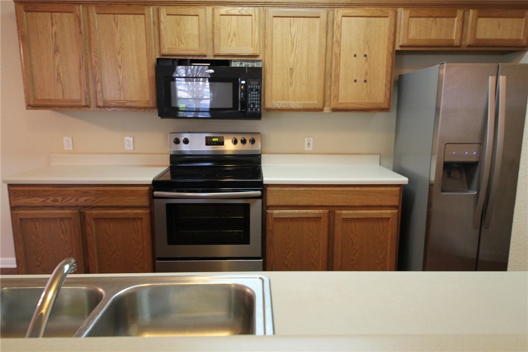 9600 Magna Carta Loop, Unit 177 Austin, TX 78754 - Photo 6 of 25 a kitchen with stainless steel appliances wooden cabinets and a stove top oven