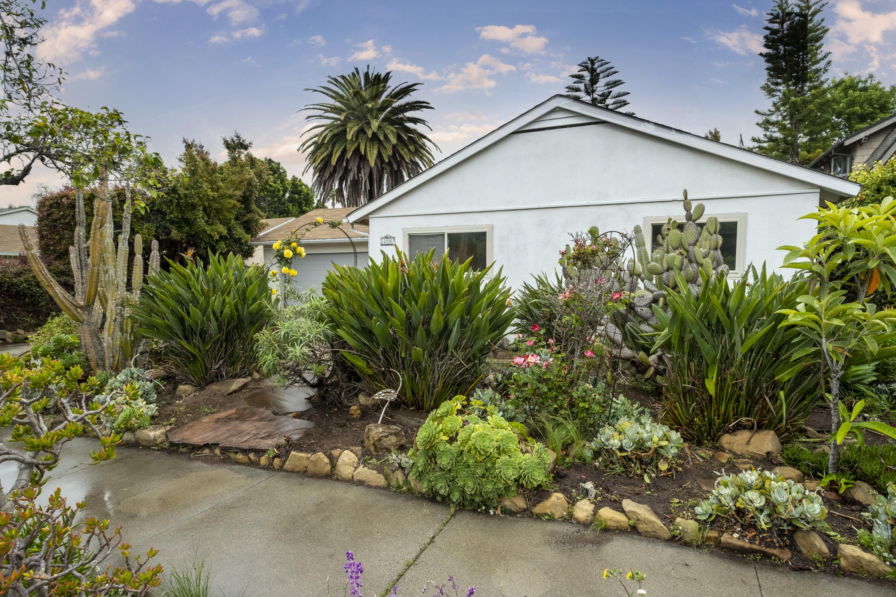 2530 Murrell Road Santa Barbara, CA 93109 - Photo 1 of 19 a white house with a small yard plants and large trees