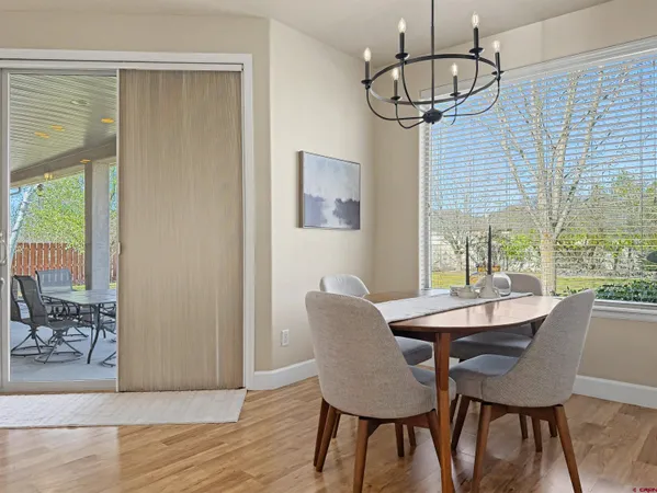 a dining room with wooden floor a chandelier a glass table and chairs