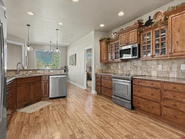 a kitchen with stainless steel appliances kitchen island granite countertop a stove a sink and white cabinets