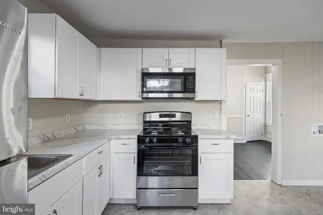 a kitchen with granite countertop white cabinets and stainless steel appliances