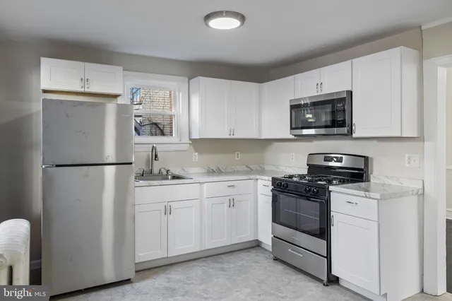 a kitchen with stainless steel appliances granite countertop white cabinets a refrigerator a stove a sink and a microwave