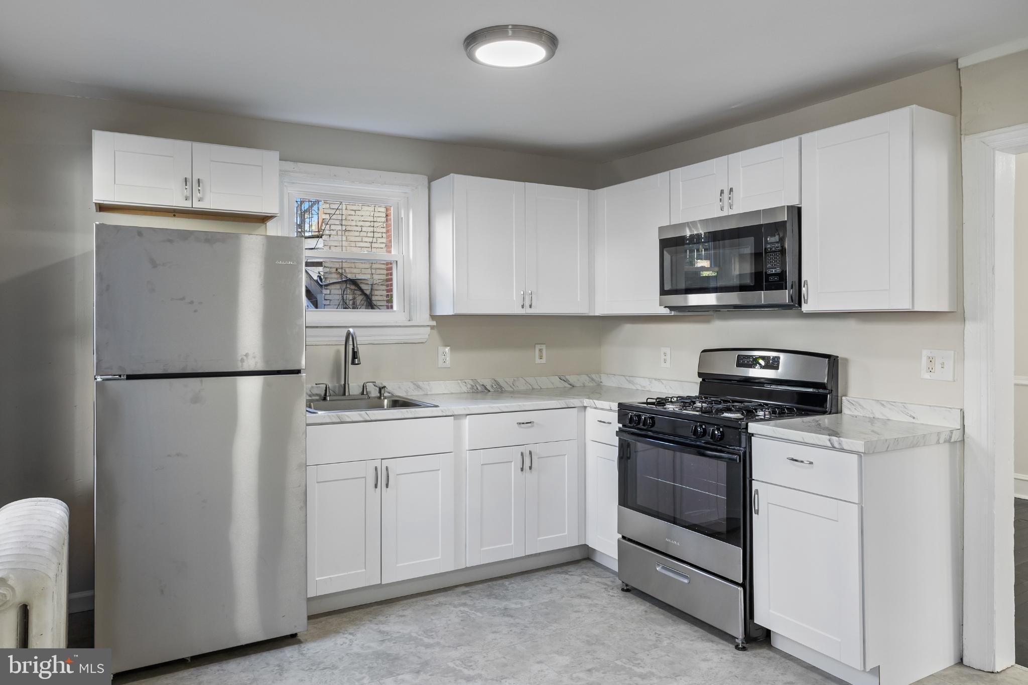 2003 Edgmont Avenue Chester, PA 19013 - Photo 23 of 40 a kitchen with stainless steel appliances granite countertop white cabinets a refrigerator a stove a sink and a microwave
