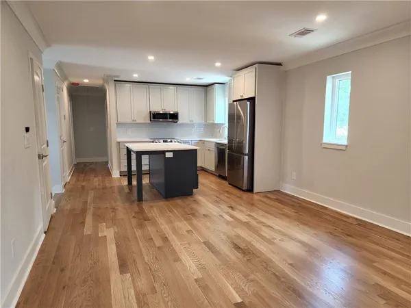 a view of kitchen with stainless steel appliances granite countertop a refrigerator oven a sink dishwasher and a refrigerator with wooden floor