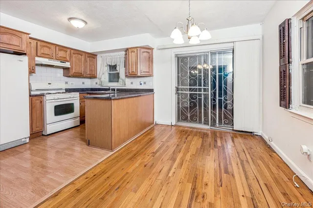 a kitchen with granite countertop wooden floors a sink stainless steel appliances and cabinets