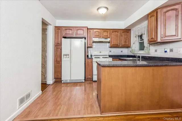 a kitchen with stainless steel appliances granite countertop a refrigerator a sink and white cabinets