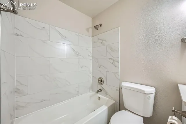 a white toilet and tub sitting next to a bathroom sink
