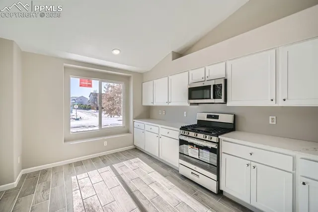 a kitchen with granite countertop appliances cabinets and a window