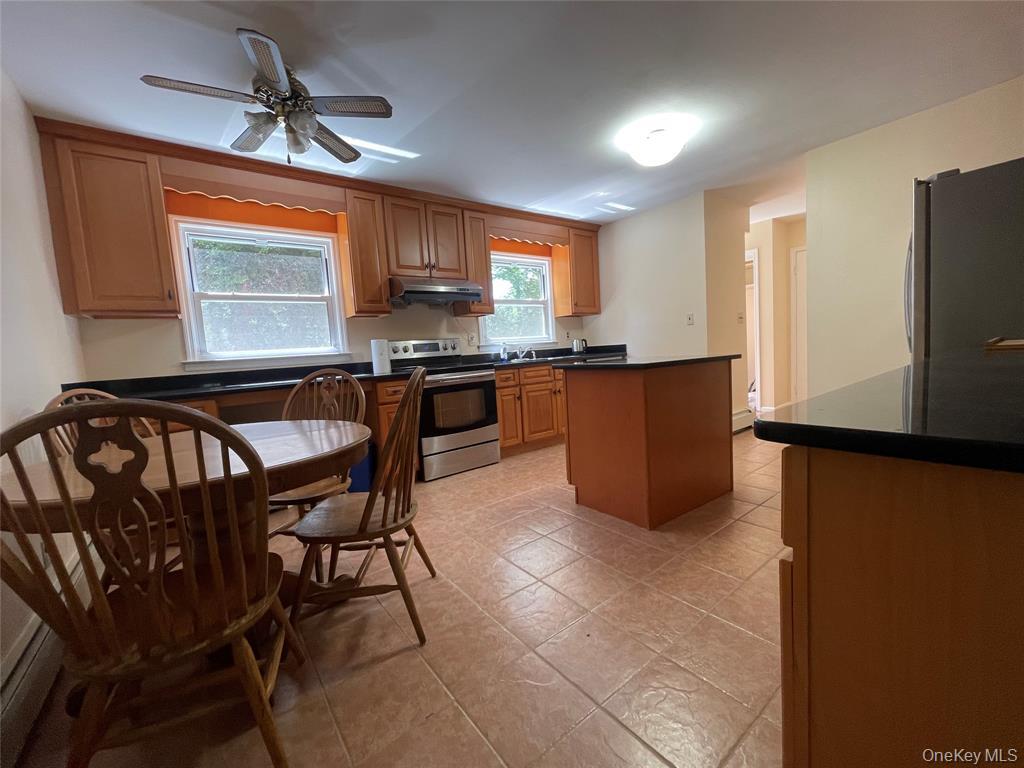 4 Cornwallis Road East Setauket, NY 11733 - Photo 4 of 16 a kitchen with stainless steel appliances granite countertop a stove a refrigerator a sink a dining table and chairs with the front door