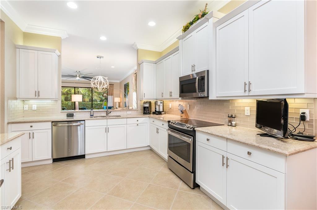 13628 Mandarin Circle Naples, FL 34109 - Photo 6 of 48 a kitchen with granite countertop white cabinets and white appliances