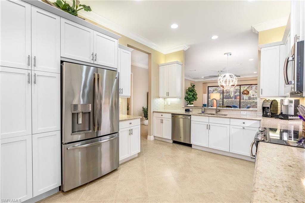13628 Mandarin Circle Naples, FL 34109 - Photo 9 of 48 a kitchen with white cabinets and stainless steel appliances