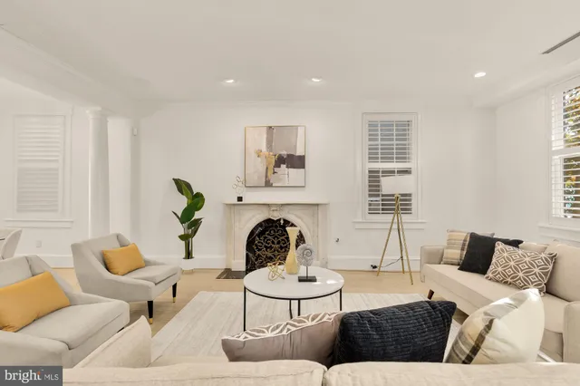 a living room with furniture a fireplace and floor to ceiling windows