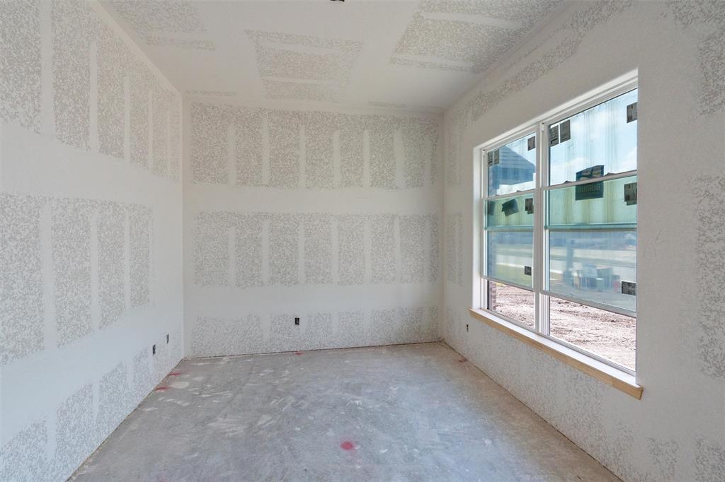 Unfinished interior space featuring drywall installation and a large window with multiple panes