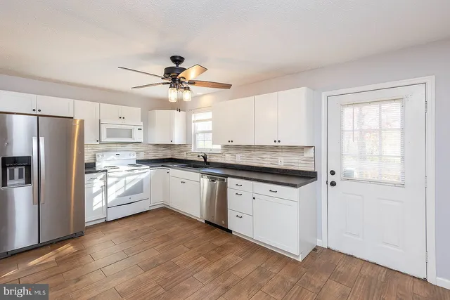 a kitchen with granite countertop white cabinets and white appliances