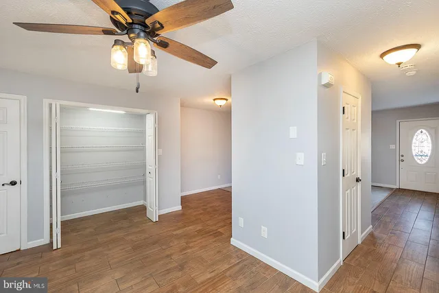 an empty room with wooden floor closet and fan