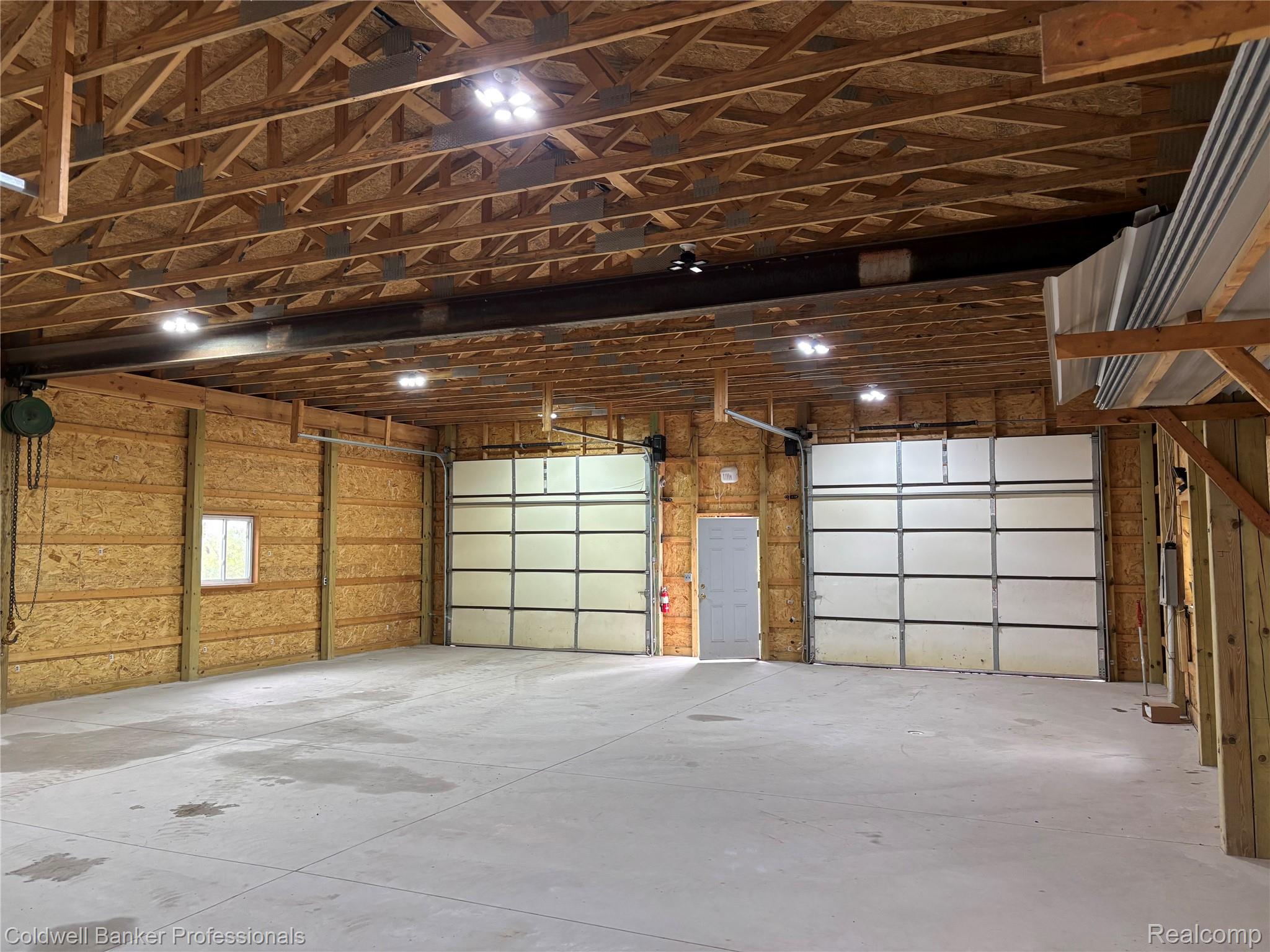 11560 Ashman Hl Road Boyne Falls, MI 49713 - Photo 19 of 22 Pole barn featuring a concrete floor, exposed wood ceiling trusses, and multiple overhead lighting fixtures