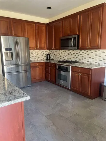 a kitchen with granite countertop wooden cabinets a refrigerator and a sink