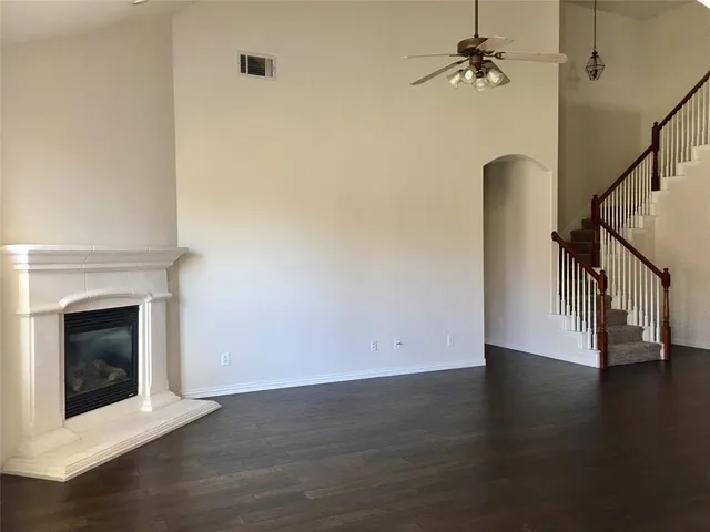 a view of an empty room with wooden floor and a fireplace