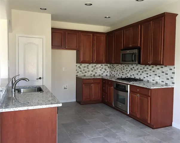 a kitchen with stainless steel appliances granite countertop wooden cabinets a stove and a sink