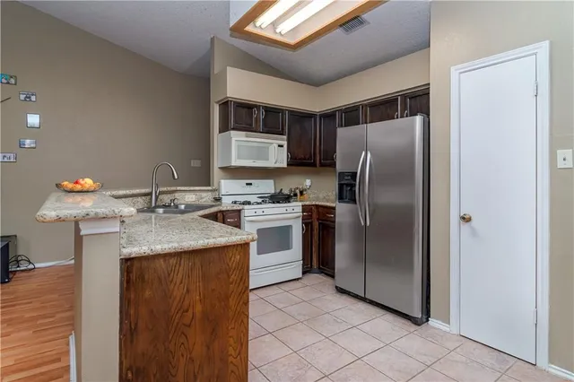 a kitchen with stainless steel appliances granite countertop a refrigerator a sink a stove and island