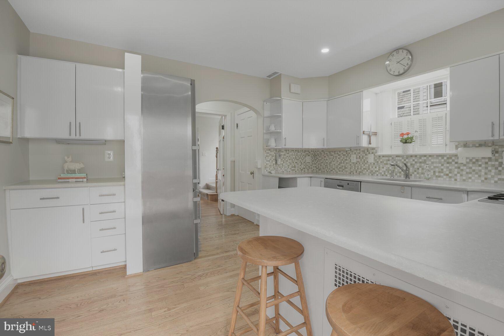 6011 Broad Branch Road Northwest Washington, DC 20015 - Photo 9 of 27 a kitchen with a sink a stove a refrigerator and white cabinets