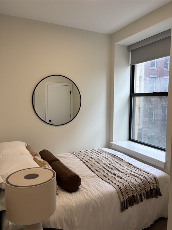 47 Winter Street, Unit 601 Boston, MA 02108 - Photo 7 of 12 a bedroom with a bed and a mirror