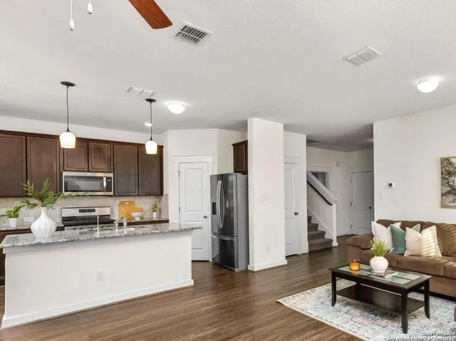 a kitchen with stainless steel appliances wooden floor and a view of living room