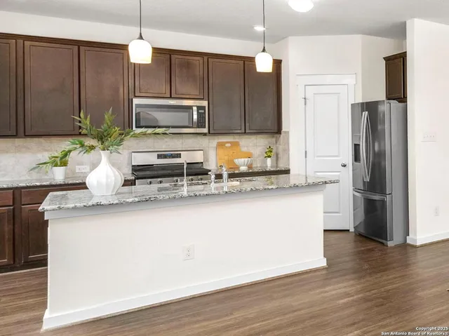 a kitchen with stainless steel appliances granite countertop a refrigerator a sink a stove a microwave and wooden floors