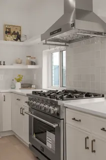 a dining hall with stainless steel appliances a sink dishwasher a refrigerator and a dining table with wooden floor