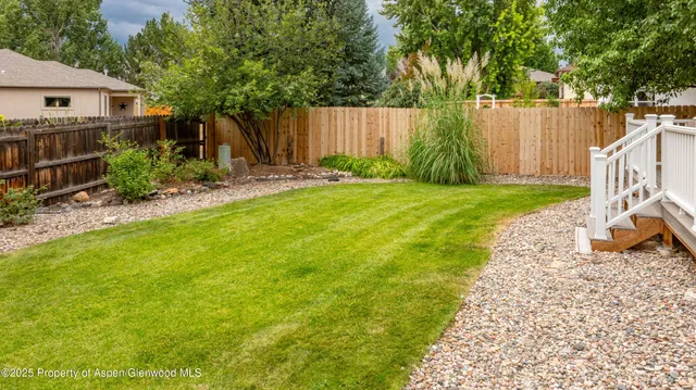 a view of backyard with a table and chairs a fire pit and grass
