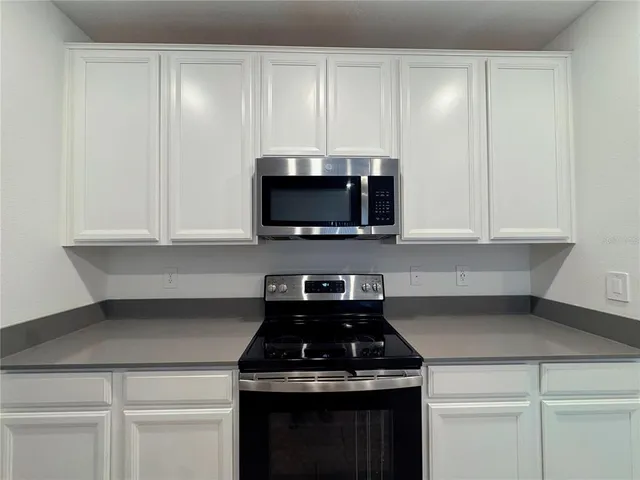 a kitchen with granite countertop white cabinets and black appliances