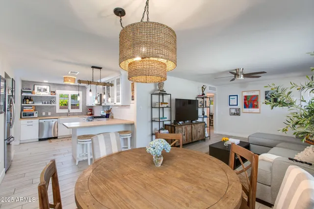 a kitchen with stainless steel appliances granite countertop a sink dishwasher a stove a dining table and chairs with wooden floor