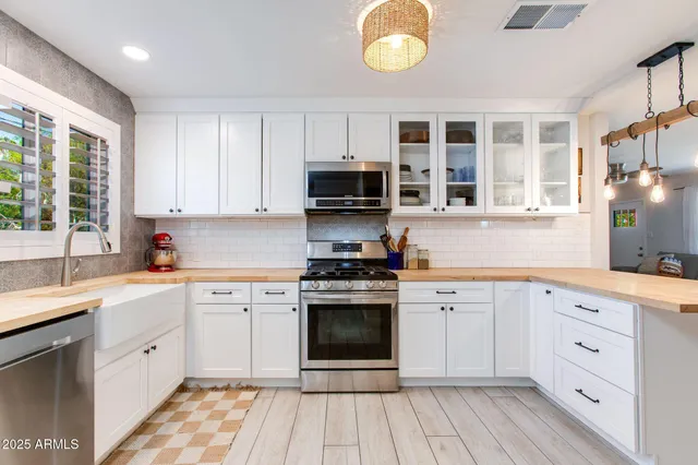 a kitchen with cabinets stainless steel appliances a sink and a window