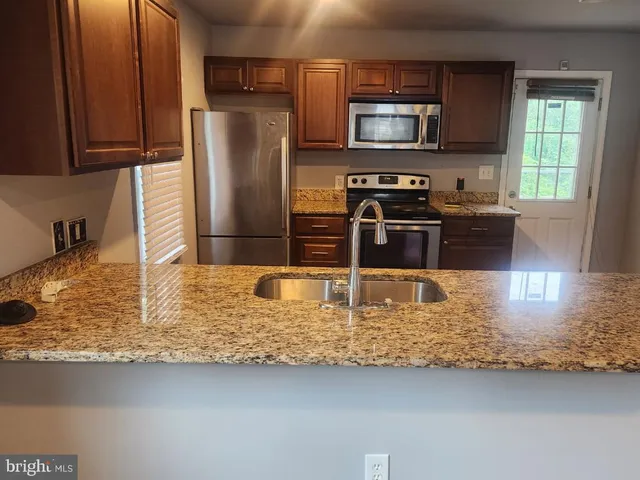 a kitchen with stainless steel appliances granite countertop a refrigerator a stove top oven a sink and dishwasher