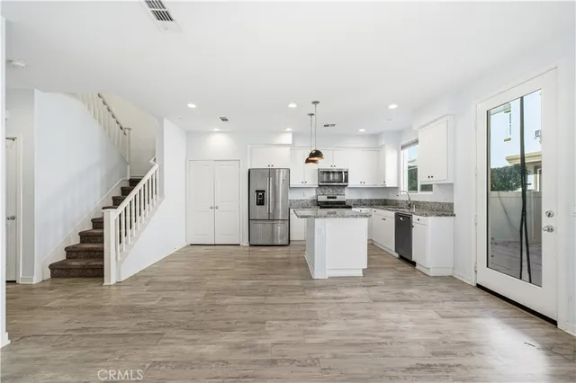 a view of kitchen with stainless steel appliances kitchen island granite countertop a refrigerator and a stove top oven