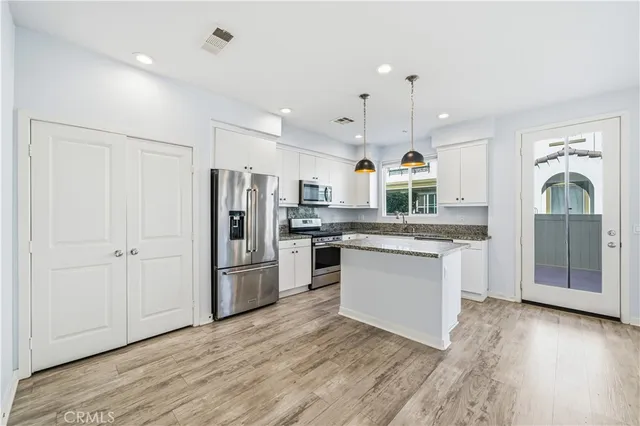 a kitchen with stainless steel appliances granite countertop a refrigerator and a stove top oven