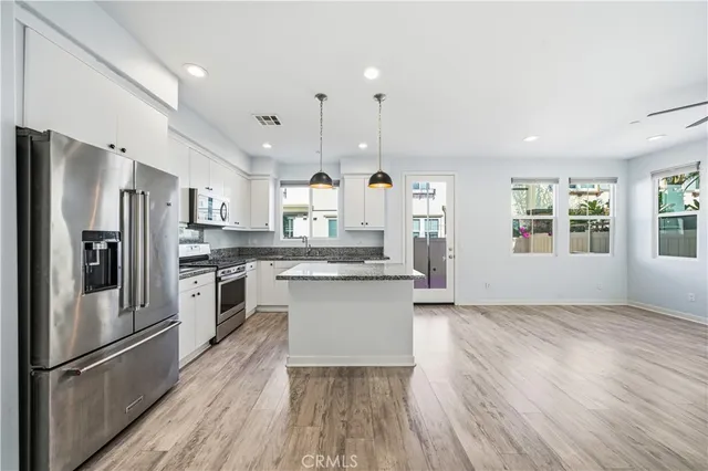 a kitchen with granite countertop stainless steel appliances a refrigerator cabinets and wooden floor