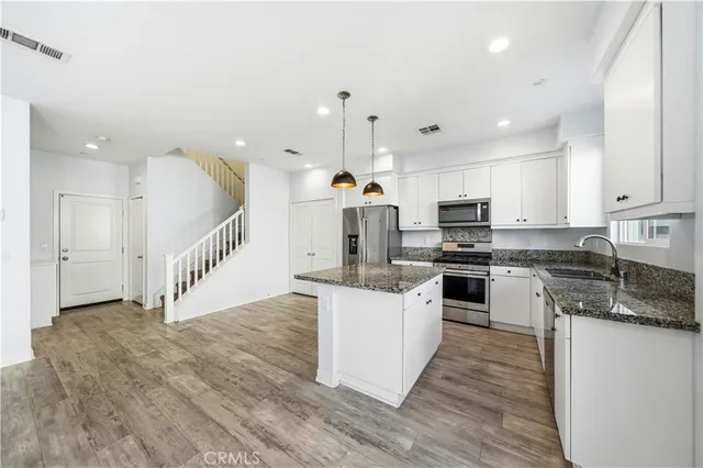 a kitchen with stainless steel appliances kitchen island granite countertop a stove a sink and a refrigerator