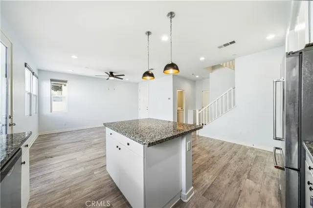 a kitchen with stainless steel appliances granite countertop a refrigerator a sink and a wooden floor