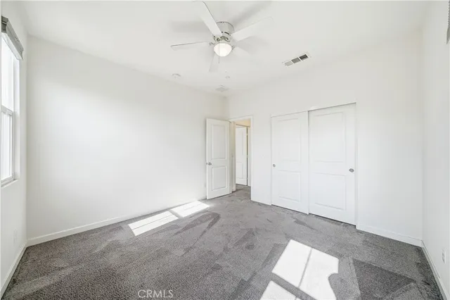 an empty room with a ceiling fan and window